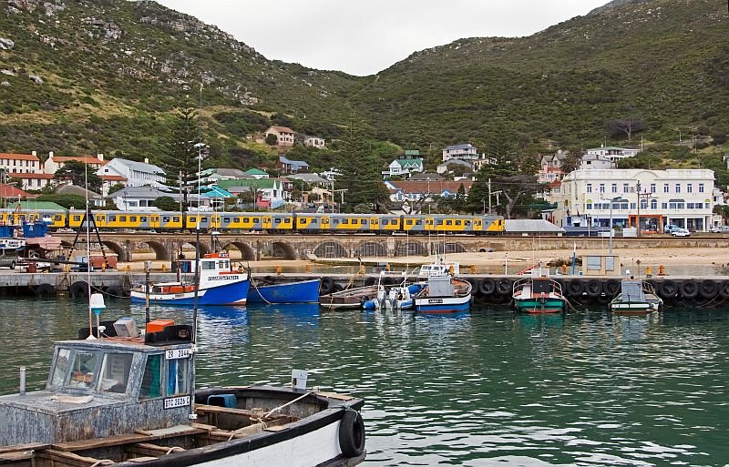 Metrorail train is passing the harbor of Kalk Bay