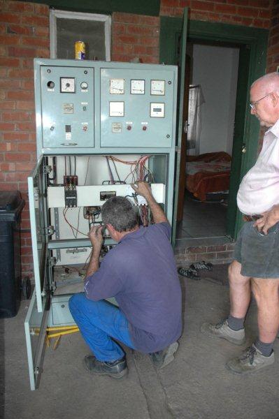 Tom keeps an eye on Steve, as he figures out the wiring system in the main switchboard.
