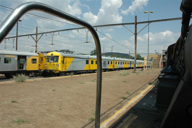 Steam looks on at the two faces of the Metro sets, as 3664 waits for signals at Pretoria North.