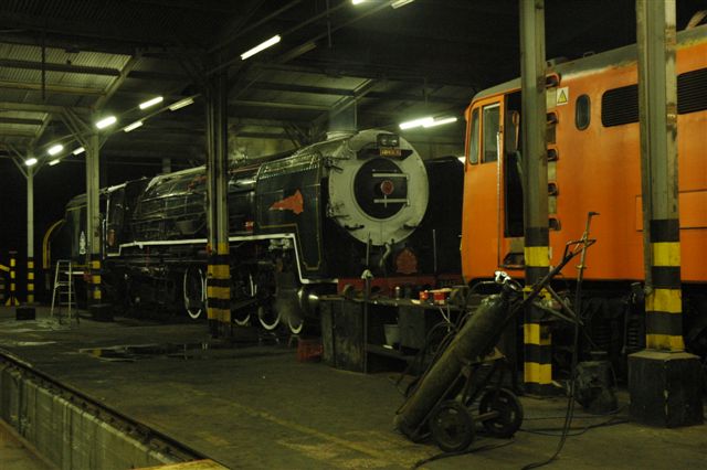 The ex 15M shop at the old steam depot Capital Park is now home to the Rovos Rail fleet. Simmering away between shifts is 25NC 3442, whilst the new face of future motive power, class 5E1, looks on