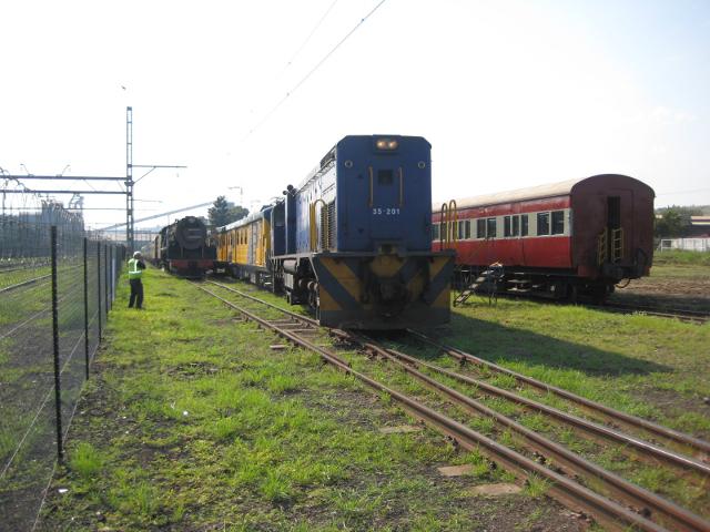 A diesel loco propels an electric Metro past a steam engine