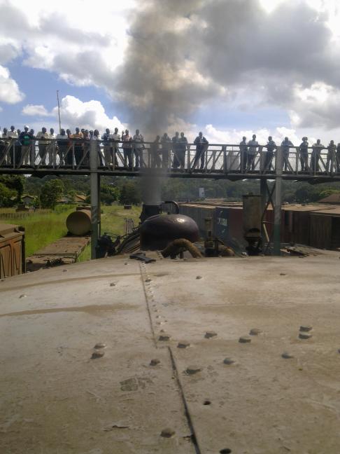 The footbridge across the Nairobi marshalling yard is lined with spectators, both the media and the public
