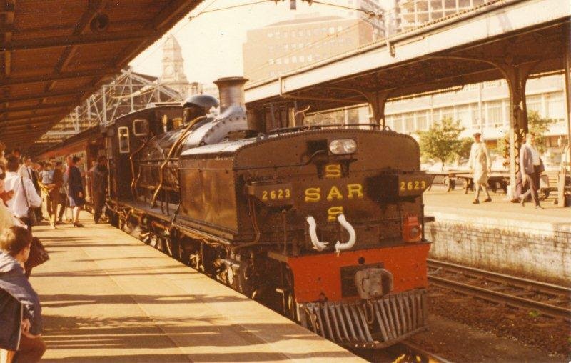 Farewell to steam on the South Coast line was worked from Durban to Port Shepstone by two class GCA garratts. Pictured here and ready to depart from Durban is 2623. Number 2199 was sent ahead and waited as standby loco at Kelso. They double headed back. 1971.