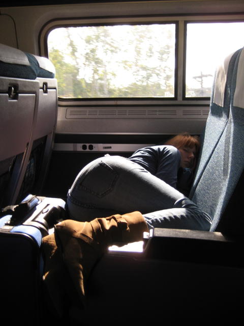 A passenger sleeps comfortably, taking up two seats, boots on the seat. Maybe that's considered normal in the USA?