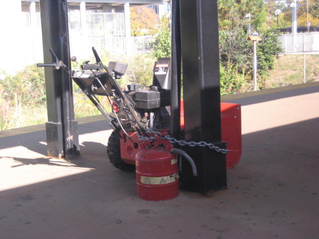 A snow-blower chained to the pillar on the platform of a small station