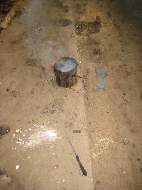 A boilermaker's tool - a long piece of wire with a bit of cotton waste tied on the end, and fire in a pot to light it with. Not sure about the sock...