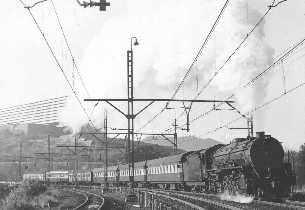 First light and the morning train from Cullinan enters Pretoria station, with the imposing UNISA building hanging on in the background. Three times weekly this scene was repeated with the train departing Cullinan via Rissik at 06:15 am. All stops to Koedoespoort. Since 2010 the Rayton to Cullinan section has been the venue for sleeper thieves and recently a lot of steel sleepers were relocated, resulting in FOTR having to bus the passengers from Rayotn to Cullinan. This scene was early 1982