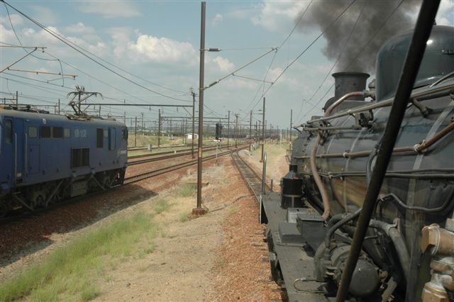 A brace of 18E electric locomotives is held in the hole for the FOTR Tshwane Xplorer. Drifting down into the main yard, a good fire has been laid on for the clmb around the balloon at Pyramid South yard