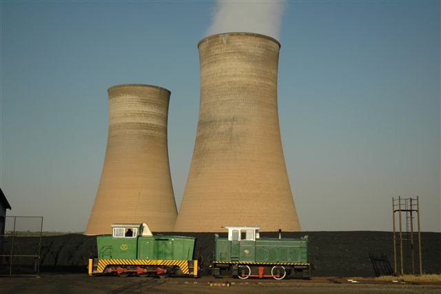The massive cooling towers of the Rooiwal Power Station dwarf the two diesel shunters used by the company. Pictured here on the departure road from their small shed