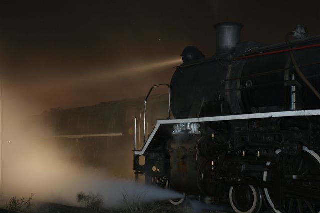 Steam from the cylinder cocks shrouds the 15F, the headlight illuminating the scene ahead.