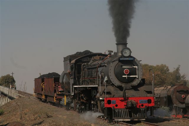 Driver Cliff has 2650 in hand as she storms the coalstage with 2 coal hoppers; 3117 looks on patiently.