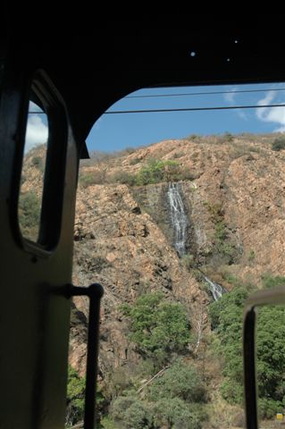 Framed by the cab of the 19D, the man made waterfall flows. In the background can be seen the dark entrances of the caves. Many a time, people can be seen sitting there looking down at the passing trains