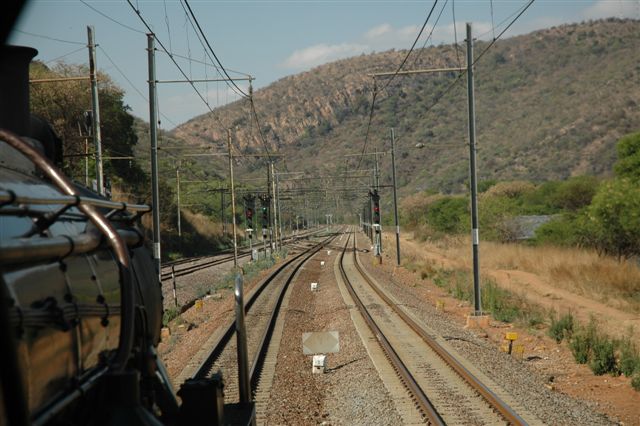 Drifting down towards Wonderboompoort, the mountains look down upon the train. On the righthand koppie, is a man made waterfall and a number of small caves
