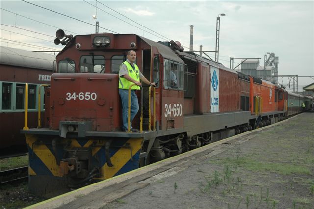34 class diesels in two different liveries stand ready to depart the Hercules Friends Of The Rail site, with a six coach charter to Bela Bela (Warmbaths). The lead loco was used regularly on the Zimbabwean BBR line from Beit Bridge to West Nicolson. Driver Wimpy Stevens gives us a pose