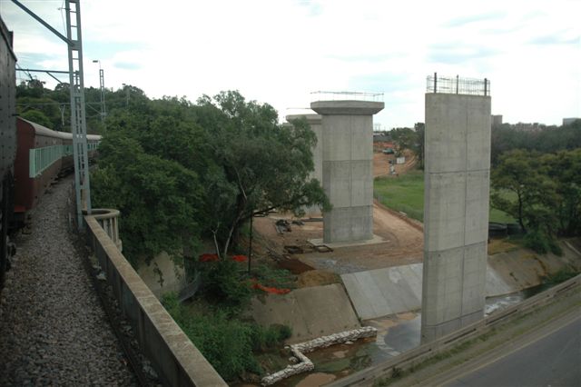 Steam-hauled Tshwane Xplorer rolls past the new Gautrain bridge supports at the entrance to Pretoria. At this point, there are three bridges, one being the old NZASM, of which only a cut off portion exists, the current railway bridge and the soon to be Gautrain one