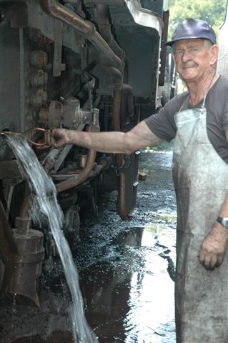 Des Paton pulls a copper rod through the washout plug opening in the front of the firebox, above the foundation ring. He has been scratching out all the accumulation of scale and grunge that forms in loco boilers, hence, like any kettle at home, a good rinse is needed to get rid of the scale etc